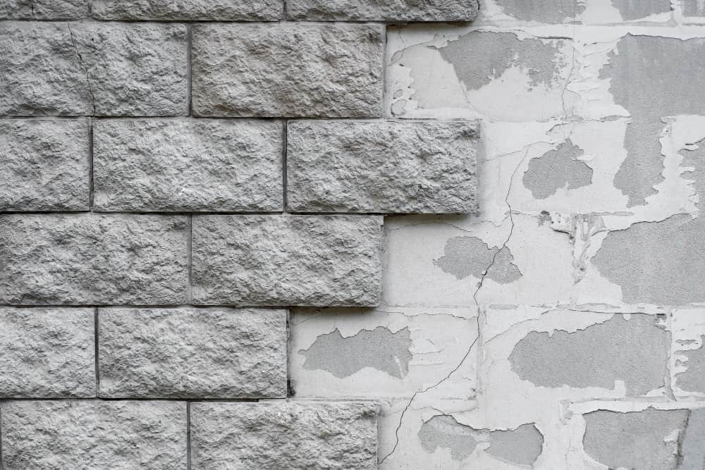 Close-up of rough gray bricks beside cracked, peeling plaster—creates a rustic, aged contrast.